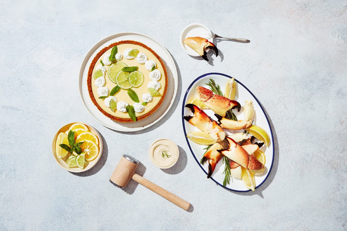 Stone crab claw dinner with key lime pie, citrus slices, sauces, and a wooden mallet