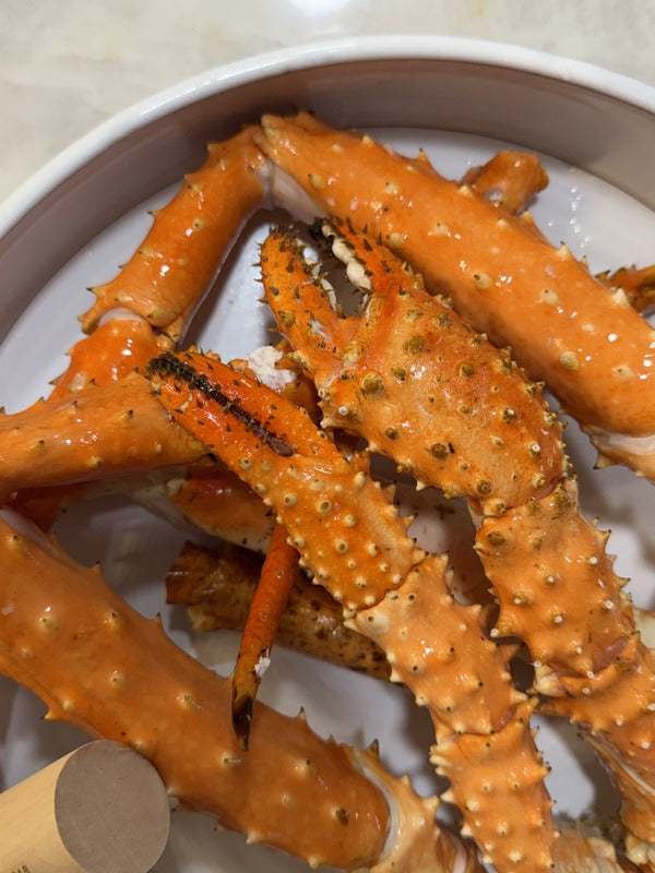 Alaskan King Crab legs in a white container on a light-colored surface